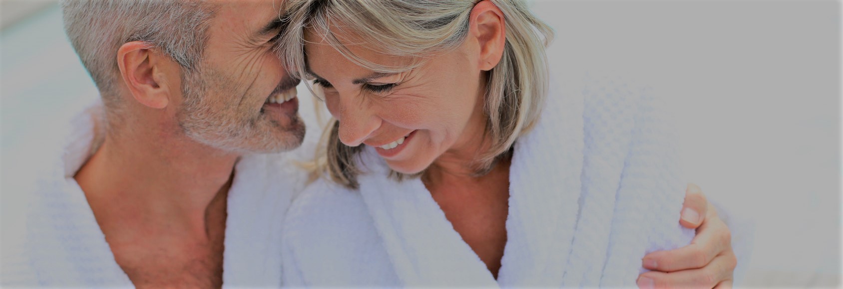 Happy senior couple in bathrobe by resort pool